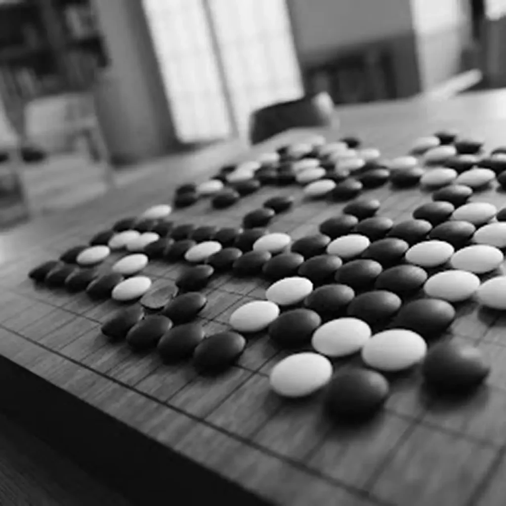 Een houten Go-bord gevuld met zwart-witte stenen tijdens een strategisch spel, vastgelegd in een zachte sepia-tint.